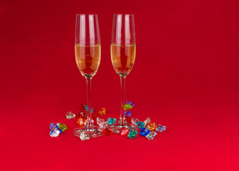 glasses of champagne on red background with sparkling crystal stones on base. New year or romantic celebration. Luxury. Free space