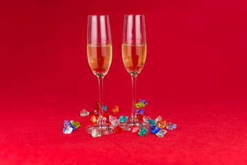glasses of champagne on red background with sparkling crystal stones on base. New year or romantic celebration. Luxury. Free space