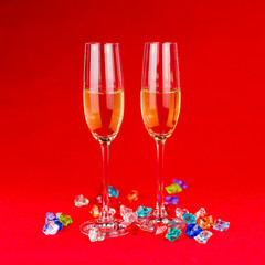 glasses of champagne on red background with sparkling crystal stones on base. New year or romantic celebration. Luxury. Free space