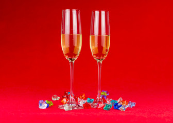 glasses of champagne on red background with sparkling crystal stones on base. New year or romantic celebration. Luxury. Free space