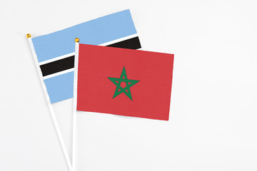 Morocco and Botswana stick flags on white background. High quality fabric, miniature national flag. Peaceful global concept.White floor for copy space.
