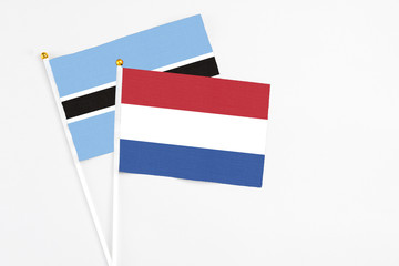 Netherlands and Botswana stick flags on white background. High quality fabric, miniature national flag. Peaceful global concept.White floor for copy space.