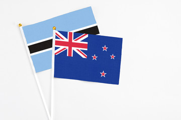 New Zealand and Botswana stick flags on white background. High quality fabric, miniature national flag. Peaceful global concept.White floor for copy space.