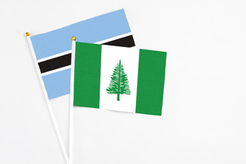 Norfolk Island and Botswana stick flags on white background. High quality fabric, miniature national flag. Peaceful global concept.White floor for copy space.
