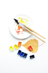 Happy autumn. Workplace with a plate, pens and watercolor palette, flat composition.