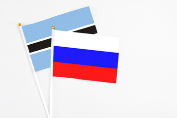 Russia and Botswana stick flags on white background. High quality fabric, miniature national flag. Peaceful global concept.White floor for copy space.