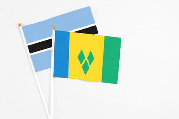 Saint Vincent And The Grenadines and Botswana stick flags on white background. High quality fabric, miniature national flag. Peaceful global concept.White floor for copy space.