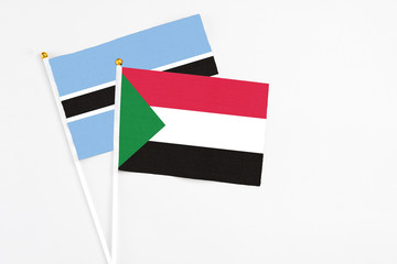 Sudan and Botswana stick flags on white background. High quality fabric, miniature national flag. Peaceful global concept.White floor for copy space.