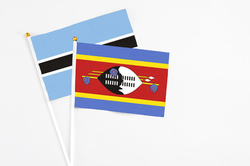 Swaziland and Botswana stick flags on white background. High quality fabric, miniature national flag. Peaceful global concept.White floor for copy space.