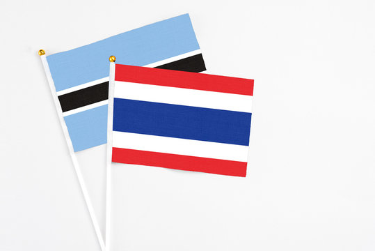 Thailand and Botswana stick flags on white background. High quality fabric, miniature national flag. Peaceful global concept.White floor for copy space.