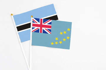Fototapeta premium Tuvalu and Botswana stick flags on white background. High quality fabric, miniature national flag. Peaceful global concept.White floor for copy space.