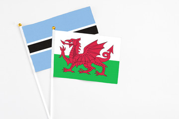 Wales and Botswana stick flags on white background. High quality fabric, miniature national flag. Peaceful global concept.White floor for copy space.