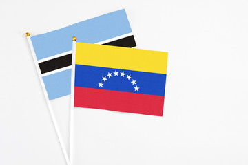 Venezuela and Botswana stick flags on white background. High quality fabric, miniature national flag. Peaceful global concept.White floor for copy space.
