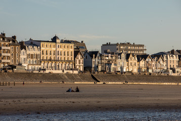 Fototapeta na wymiar Beach in the evening sun and buildings along the seafront promenade in Saint Malo. Brittany, France