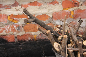 brushwood in a bucket for a stove or fireplace near a brick wall. Old firewood basket on a rustic wooden floor