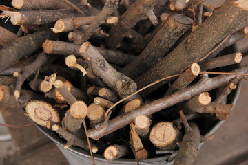 brushwood in a bucket for a stove or fireplace near a brick wall. Old firewood basket on a rustic wooden floor