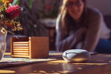 Woman talking to voice controlled smart speaker in a living room. 
