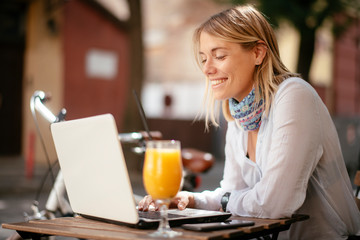 Young woman in cafe. Beautiful businesswoman drinking juice. Pretty student in cafe with lap top.