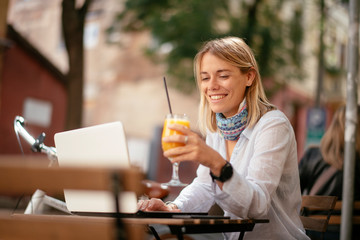 Young woman in cafe. Beautiful businesswoman drinking juice. Pretty student in cafe with lap top.