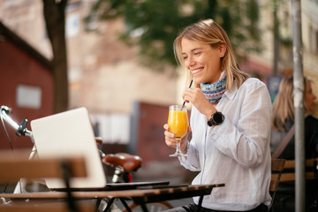 Young woman in cafe. Beautiful businesswoman drinking juice. Pretty student in cafe with lap top.