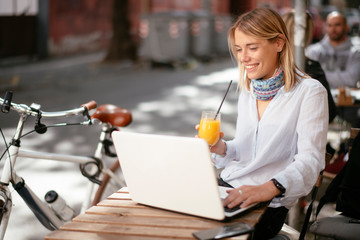 Young woman in cafe. Beautiful businesswoman drinking juice. Pretty student in cafe with lap top.