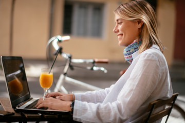 Young woman in cafe. Beautiful businesswoman drinking juice. Pretty student in cafe with lap top.