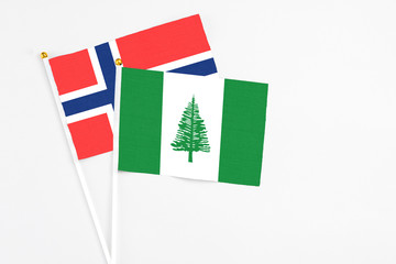 Norfolk Island and Bouvet Islands stick flags on white background. High quality fabric, miniature national flag. Peaceful global concept.White floor for copy space.