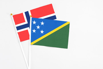 Solomon Islands and Bouvet Islands stick flags on white background. High quality fabric, miniature national flag. Peaceful global concept.White floor for copy space.