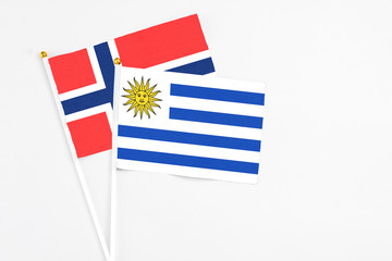 Uruguay and Bouvet Islands stick flags on white background. High quality fabric, miniature national flag. Peaceful global concept.White floor for copy space.