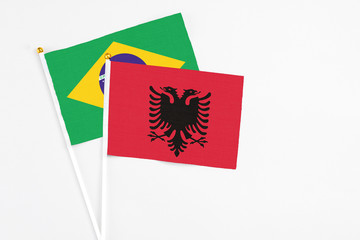 Albania and Brazil stick flags on white background. High quality fabric, miniature national flag. Peaceful global concept.White floor for copy space.