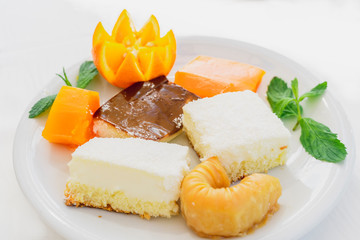 Oriental sweets decorated with orange on a white plate on white background