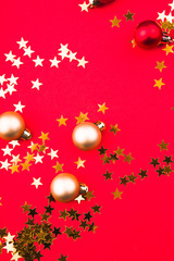 Fototapeta na wymiar Top view composition of red christmas balls and gold stars on a red background.
