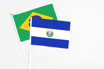 El Salvador and Brazil stick flags on white background. High quality fabric, miniature national flag. Peaceful global concept.White floor for copy space.