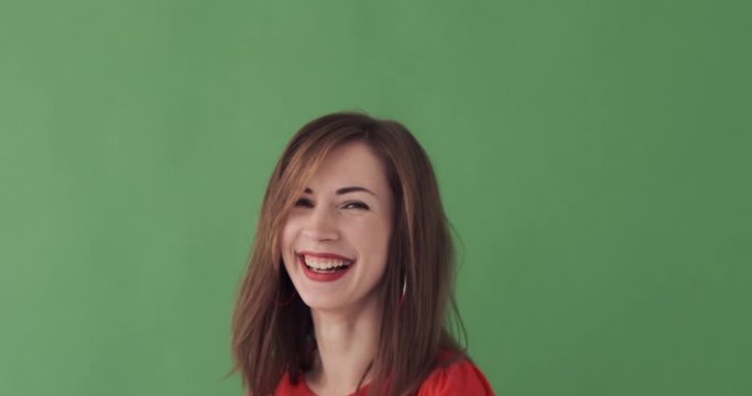 Beautiful young woman laughing out loud over green background