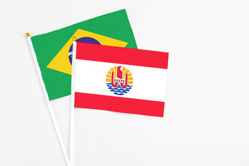 French Polynesia and Brazil stick flags on white background. High quality fabric, miniature national flag. Peaceful global concept.White floor for copy space.