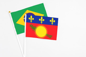 Guadeloupe and Brazil stick flags on white background. High quality fabric, miniature national flag. Peaceful global concept.White floor for copy space.