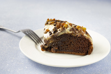 Delicious chocolate cake with raisins and cream. Piece of Chocolate Cake on a Plate. Sweet food. Sweet dessert. Light bakcground. Close up.