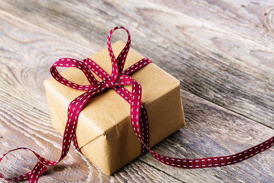 Gift box with red ribbon and bow on wooden background