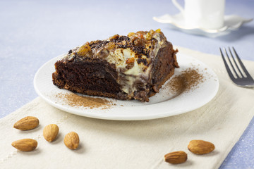 Delicious chocolate cake with raisins, almond and cream. Piece of Chocolate Cake on a Plate. Sweet food. Sweet dessert. Light bakcground. Close up.