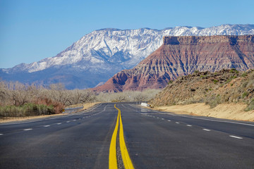 LOW ANGLE: Empty road runs through a national park and towards snowy mountains