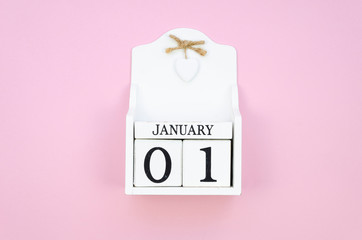 Top view white January 01 wooden cube calendar on a pink background. New Year concept