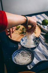 Woman hand putting some rice noodles in a bowl