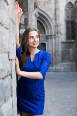 Young woman is posing in blue dress near old wall