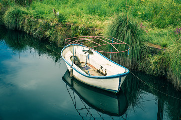 small fishing boat moored on the leafy shore of the river. serene scene