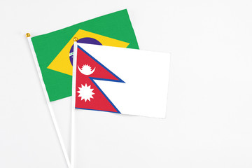Nepal and Brazil stick flags on white background. High quality fabric, miniature national flag. Peaceful global concept.White floor for copy space.