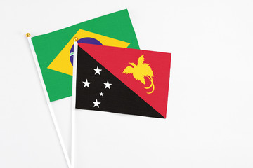 Papua New Guinea and Brazil stick flags on white background. High quality fabric, miniature national flag. Peaceful global concept.White floor for copy space.