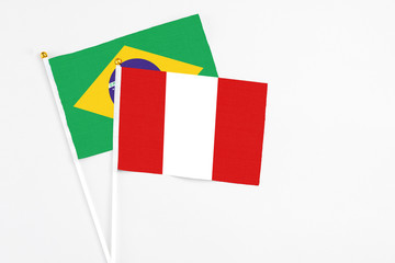 Peru and Brazil stick flags on white background. High quality fabric, miniature national flag. Peaceful global concept.White floor for copy space.