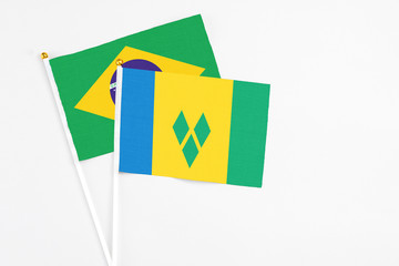 Saint Vincent And The Grenadines and Brazil stick flags on white background. High quality fabric, miniature national flag. Peaceful global concept.White floor for copy space.