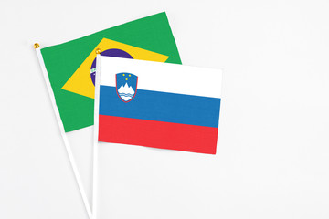 Slovenia and Brazil stick flags on white background. High quality fabric, miniature national flag. Peaceful global concept.White floor for copy space.