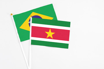 Suriname and Brazil stick flags on white background. High quality fabric, miniature national flag. Peaceful global concept.White floor for copy space.